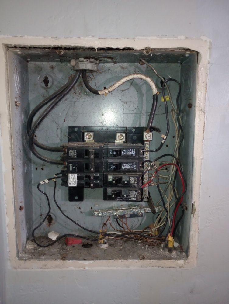 An old overloaded breaker panel with tangled wiring
